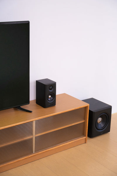 EDIFIER S355DB Black 2.1 speaker system beside a TV cabinet