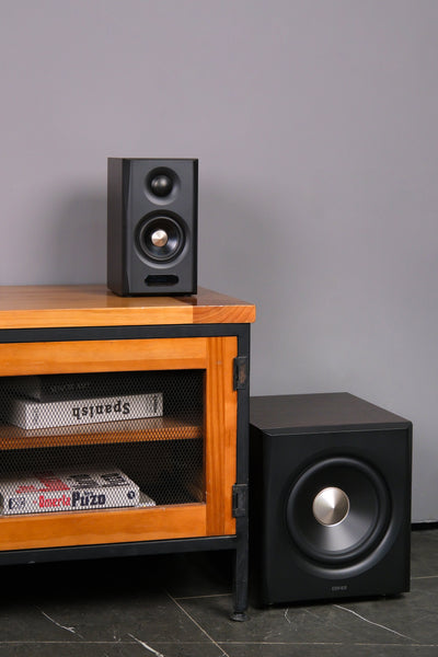 EDIFIER S355DB Walnut 2.1 speaker system satellite speaker and subwoofer beside a media cabinet